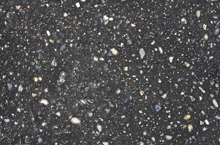 Wet dark gray asphalt texture with bright stone inclusionsの写真素材