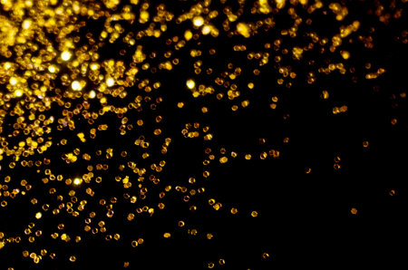 Gold glitter on black background. Holiday Christmas texture for art designの写真素材