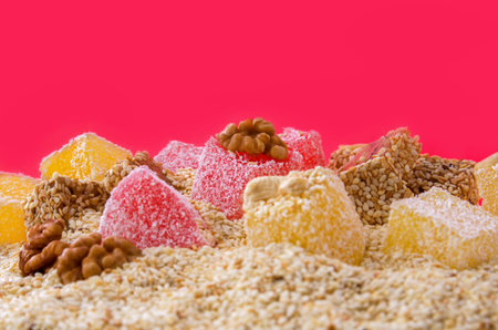 Turkish delight cubes with nut sprinkles on a bright crimson background, close-up, shallow depth of field.の写真素材