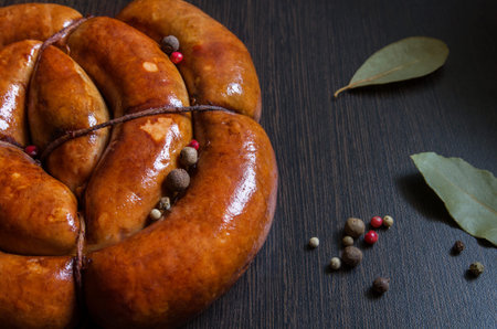Homemade fried spiral sausage made from meat with spices on the dark table background. Close up