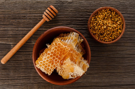 Honey combs in ceramic bowl , bee pollen and dipper on rustic wooden table