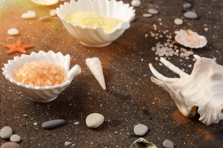 Aroma yellow and pink sea salt for bath, seashells on dark stoneの写真素材