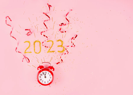 Red alarm clock on pink background with confetti and gold serpentineの写真素材