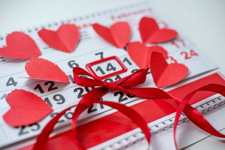 Calendar to Valentines day on the table with paper hearts