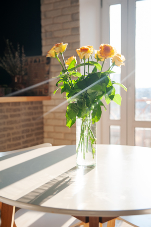 Yellow roses in a glass vase on the table in dinning room. Holidays and celebration concept. St. Valentine's Day 8 Murch and Mothers Day conceptの写真素材