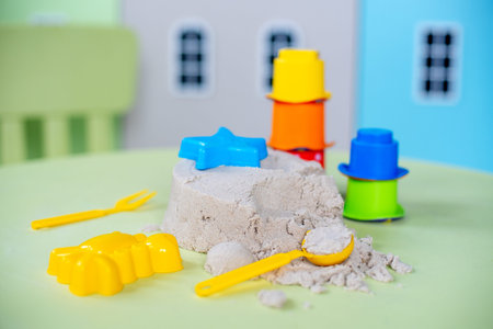 kinetic sand with toys on the green table in the children's room