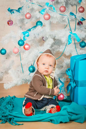 A little baby with gifts at Christmas treeの写真素材
