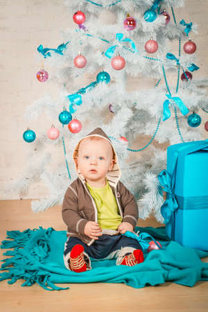 A little baby with gifts at Christmas treeの写真素材