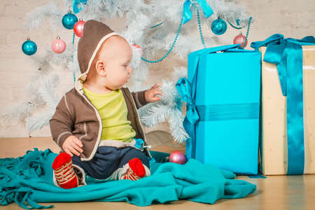 A little baby with gifts at Christmas treeの写真素材