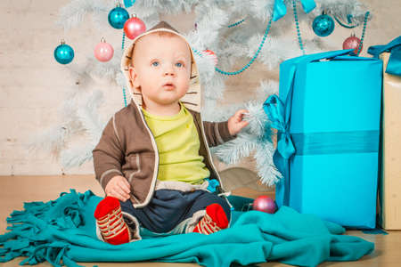 A little baby with gifts at Christmas treeの写真素材