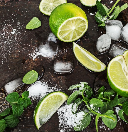 Fresh mint, slices of lime, ice, sugar over black metal surface . Top view.の写真素材