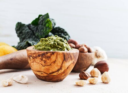 Veggie recipe - homemade pesto with kale and hazelnuts in wooden bowl on marble table with free text space. Healthy concept.の写真素材