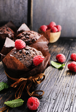 Chocolate muffins with fresh raspberries and mint on a old  black textured wooden table.Free text space.の写真素材