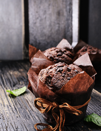 Chocolate muffins with fresh raspberries and mint on a old  black textured wooden table.Free text space.の写真素材