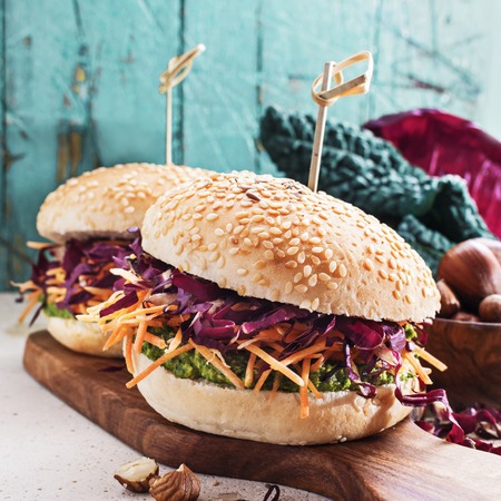 Veggie burger with pesto kale, hazelnuts, shredded carrot and red chicory on wooden board .の写真素材