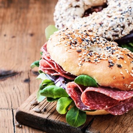 Bagels with salami and onion on a wooden board with free text space. Selective focus.の写真素材