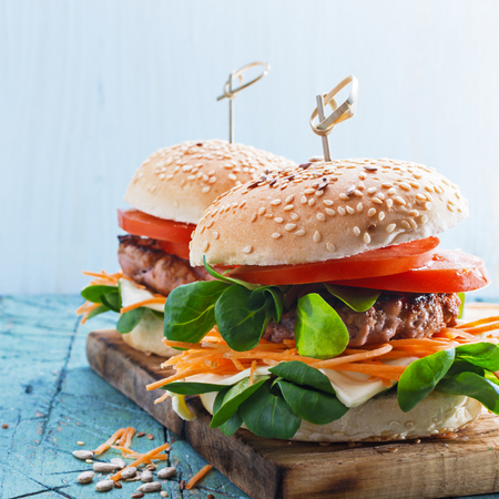 Tasty grilled  turkey burgers with corn salad and carrot,mixed seeds  served on old board on a rustic wooden table  with copyspace.の写真素材