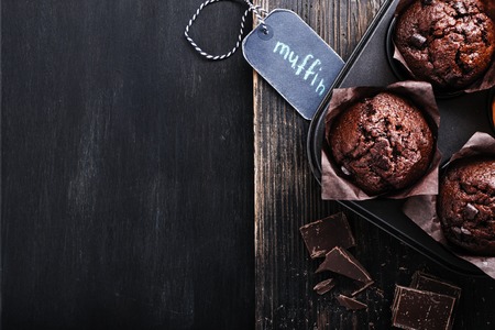 Chocolate dark muffin with a leaf of mint on a old black wooden table with  chocolate. Free text space, close up,  overhead shot with copy space.の写真素材