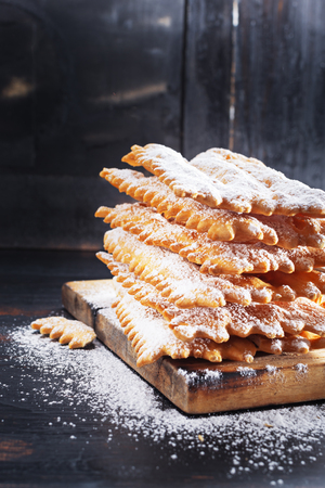 Italian Frappe or chiacchiere  - typical Italian carnival fritters dusted with powdered sugar on   old black wooden table. With free text space.の写真素材