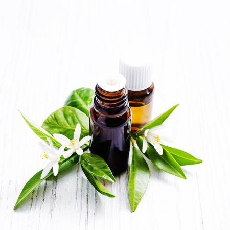 Neroli (Citrus aurantium) essential oil in a brown glass bottle with fresh white  flowers on ligth background. Selective focus.の写真素材
