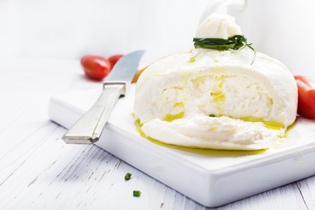 Italian burrata cheese with basil onion olive oil on white   plate on light background. Selective focus, free text space.の写真素材