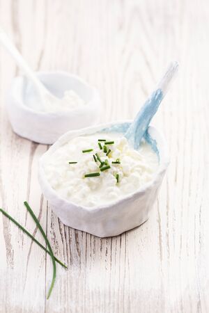 Rustic white bowl of homemade cottage cheese on a wooden marble table with copy space. Selective focus.の写真素材