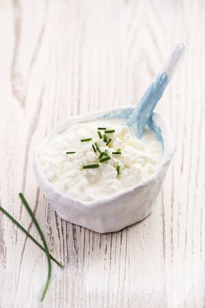 Rustic white bowl of homemade cottage cheese on a wooden marble table with copy space. Selective focus.の写真素材