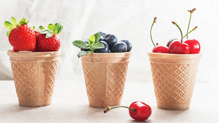 Waffle cones with fresh berries, ingredients for ice cream,sorbet or granita on marble surface.の写真素材