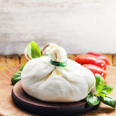 Burrata, fresh Italian cheese with red pepperoni on a wooden light background.の写真素材