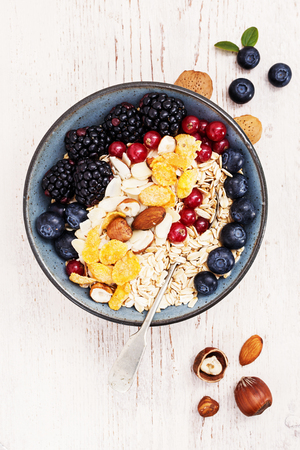 Healthy classic breakfast with oatmeal, cornflakes and various fresh berries on a white wooden surface.の写真素材