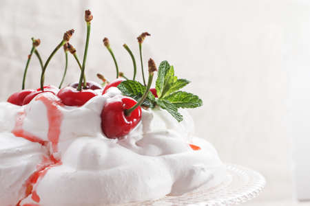 Pavlova - meringue cake with  fresh cherries  on  glass cake stand on marble background, copy space, close up, selective focus.の写真素材