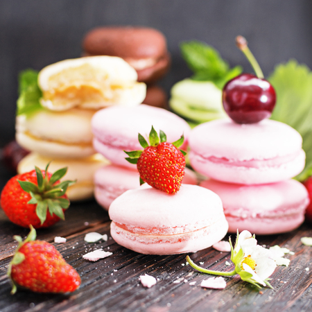Assorted colorful macaroons. Sweet macarons with fresh berries on  dark background with copy space.の写真素材
