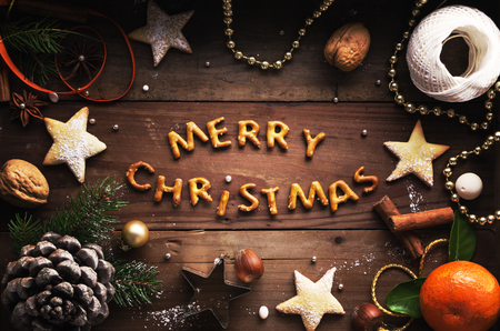 Christmas background. Cookies, sugar powder, nuts, spices, baking molds, fir-tree branch, pine cones on rustic background,  top view, copy spaceの写真素材