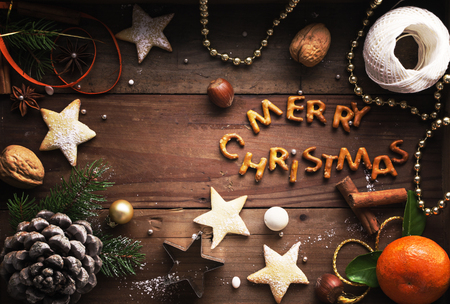 Christmas background. Cookies, sugar powder, nuts, spices, baking molds, fir-tree branch, pine cones on rustic background,  top view, copy spaceの写真素材