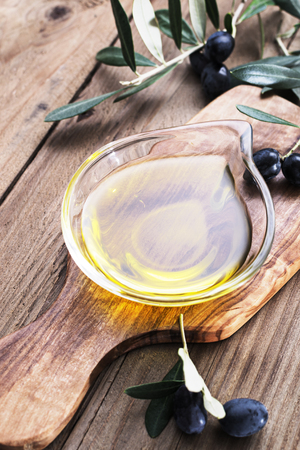 Olive oil in glass bowl on a wooden boardの写真素材