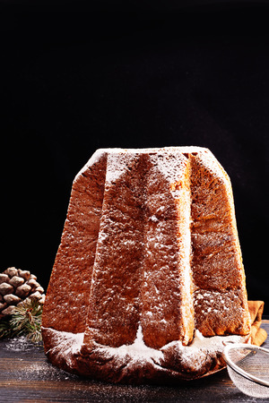 Pandoro -typical Italian christmas  sweet yeast bread on old black wooden table. With free text space.の写真素材