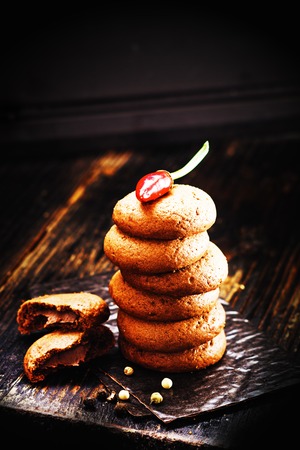 cookies with chocolate cream and chili pepper on old rustic wooden background.の写真素材