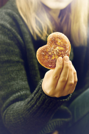 Female hands holding a doughnut shaped of heart, Valentines day and love theme