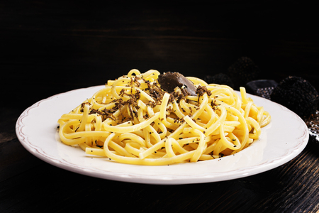 Strangozzi, italian wheat pasta with black truffle on a black wooden board.の写真素材