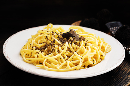 Strangozzi, italian wheat pasta with black truffle on a black wooden board.の写真素材