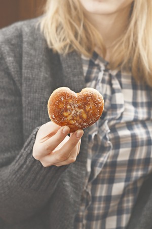 Female hands holding a doughnut shaped of heart, Valentines day and love themeの写真素材