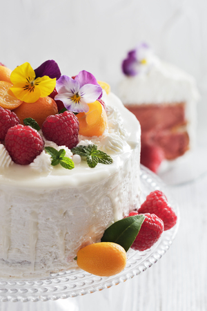 Festive cake with raspberries and flowers with streaks of glaze on  white backgroundの写真素材