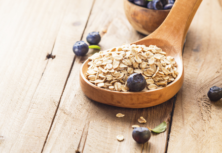 Oat flakes in wooden spoon with milk, blueberries for healthy breakfast, selective focus,の写真素材
