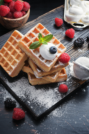 Waffles with summer raspberries served on black old rustic background.の写真素材