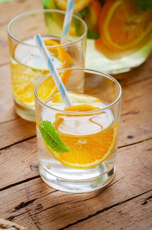 Orange infused water in glass on wooden table.の写真素材