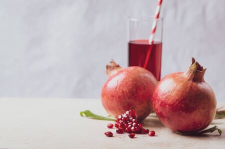 Pomegranate  with seeds and leaves  and juice in glass on light marble table.の写真素材