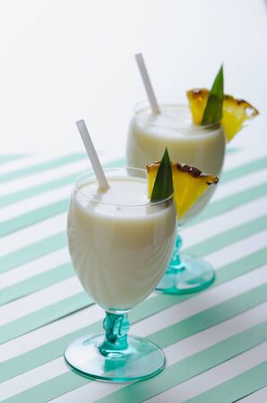 Milkshake with pineapple and coconut on green water stripes backgroundの写真素材