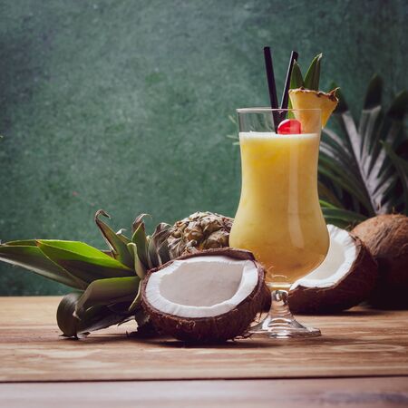 Tropical caribbean cocktail Pina Colada in a glasses on wooden  table with coconut and pineapple.の写真素材