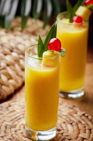 Tropical  cocktail pineapple  in a glasses, garnished with  cherries maraschino on wooden  table .の写真素材