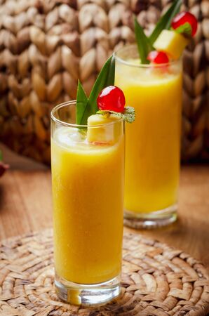 Tropical  cocktail pineapple  in a glasses, garnished with  cherries maraschino on wooden  table .の写真素材